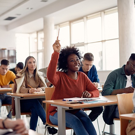 Woman smiling while raising her hand in classroom