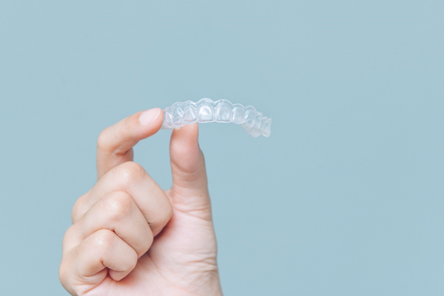 person’s hand holding clear aligner